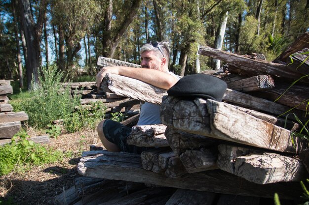 Hombre sentado en troncos de madera en el bosque