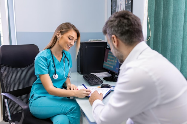 Un hombre serio consultando a una joven médica en una reunión de control en el hospital. Médico general calificado que da consejos médicos de salud al paciente.