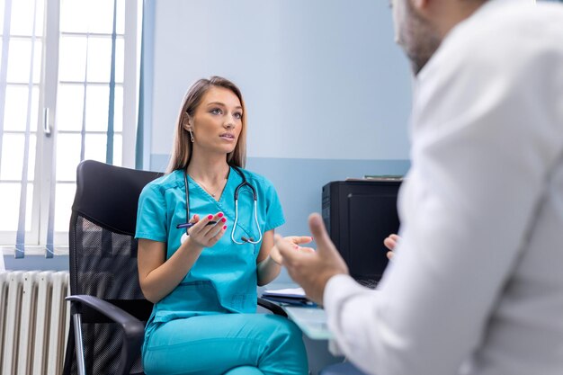 Un hombre serio consultando a una joven médica en una reunión de control en el hospital. Médico general calificado que da consejos médicos de salud al paciente.