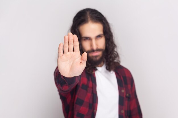 El hombre serio se detiene con la palma de la mano demuestra la prohibición y la restricción rechaza algo