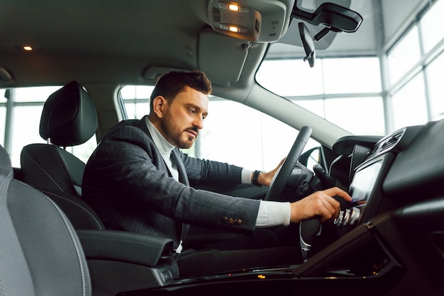 Hombre serio elegante atractivo conduce buen coche