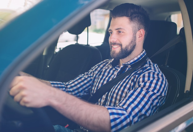 Hombre serio elegante guapo conduce un coche.