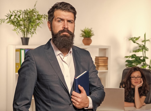 Foto hombre serio empleador profesional en traje de pie en la parte delantera mujer empleada en la oficina profesionalismo