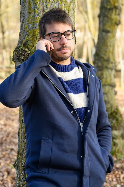 Hombre serio, hablando por teléfono móvil en un parque de otoño.