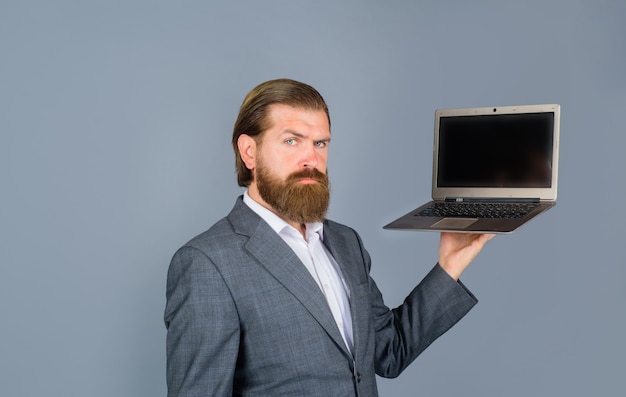 Hombre serio con ordenador portátil en la red de tecnología de oficina y hombre de negocios de internet con