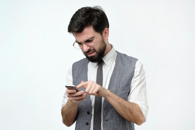 Hombre serio en traje escribiendo sms en el teléfono inteligente