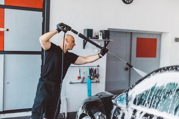 Hombre de servicio lavando automóviles antes de detallar en el taller Trabajo profesional