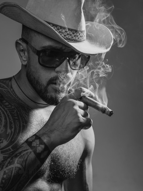 Hombre sexy fumando cigarro hombre brutal con cigarro y cara seria de modelo masculino guapo concepto de hombres