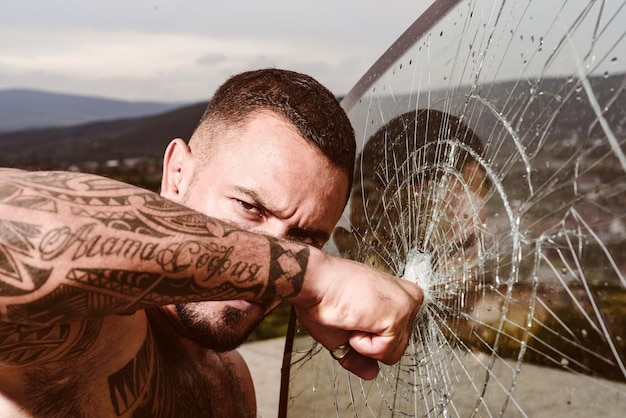 Hombre sexy con las manos peleando y rompiendo un vaso.