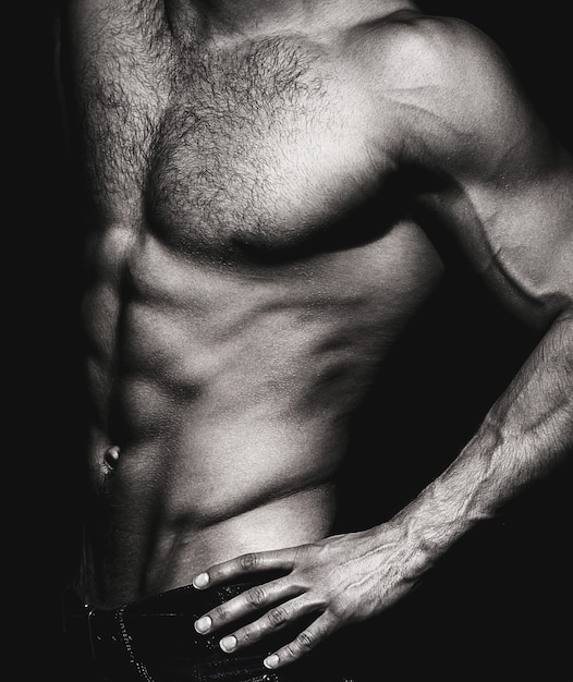 Hombre sexy musculoso con torso. modelo muscular joven deportivo sobre fondo oscuro. hombre sensual con ab fuerte desnudo. torso musculoso de cerca. concepto de torso. en blanco y negro.