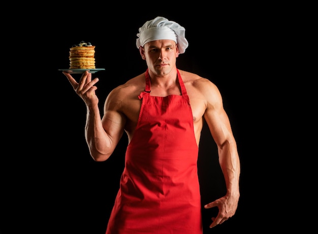 Hombre sexy con sombrero de chef con dulce pila casera de panqueques con jarabe de chef hombre musculoso con delantal ba