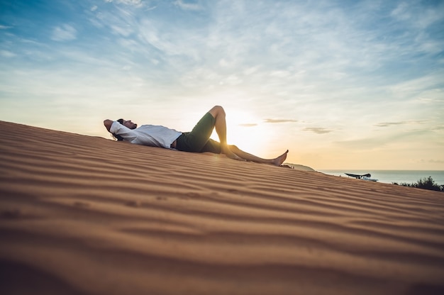 Un hombre se sienta en la arena en el desierto.