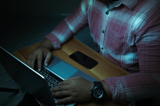 Un hombre se sienta en una computadora portátil en una habitación oscura El concepto es adicto a Internet