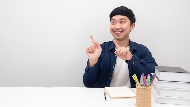 El hombre se sienta en el escritorio sonriendo y señala con el dedo el espacio de la copia