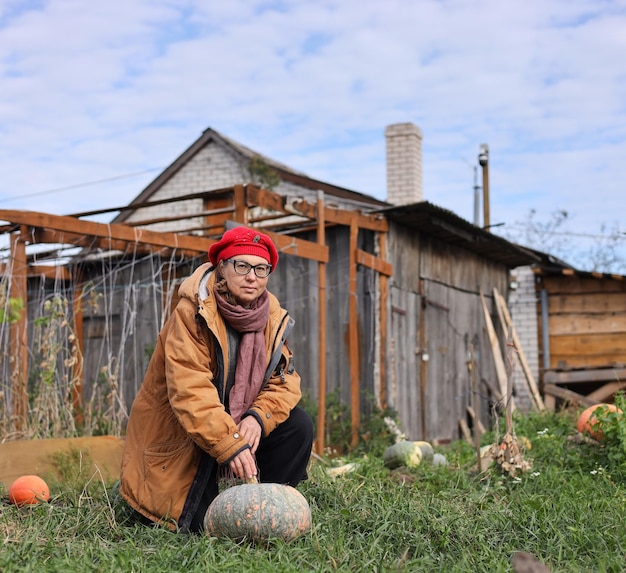 Foto un hombre se sienta frente a una casa de madera con calabazas delante de ella