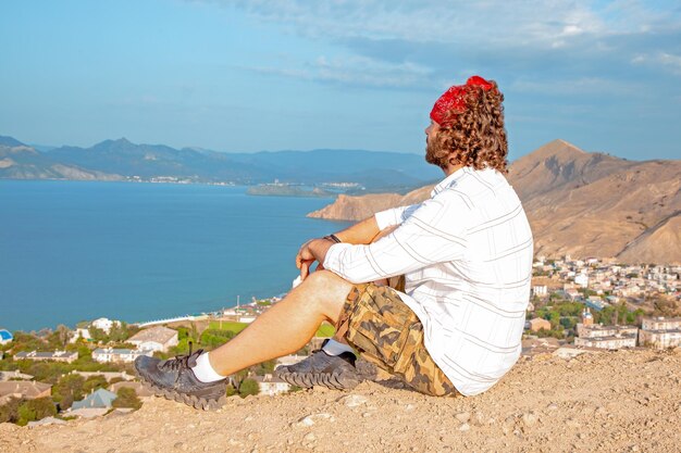 Un hombre se sienta frente a una vista panorámica de una hermosa costa