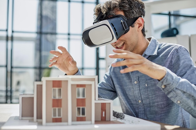 El hombre se sienta en la oficina de un agente inmobiliario y mira el diseño del apartamento en vidrio de realidad virtual