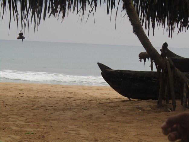 Foto un hombre se sienta en una playa al lado de un barco que está en la arena