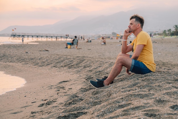 Hombre se sienta en la playa y mira el mar en la ciudad de Alanya pavo de viaje o concepto de vacaciones