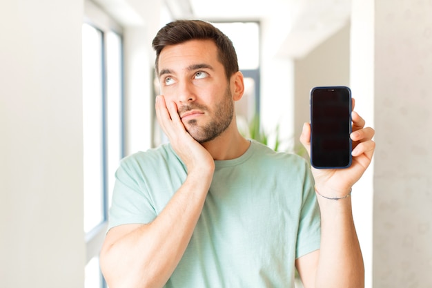 El hombre se siente aburrido, frustrado y con sueño después de una tarea tediosa, aburrida y tediosa, sosteniendo la cara con la mano.