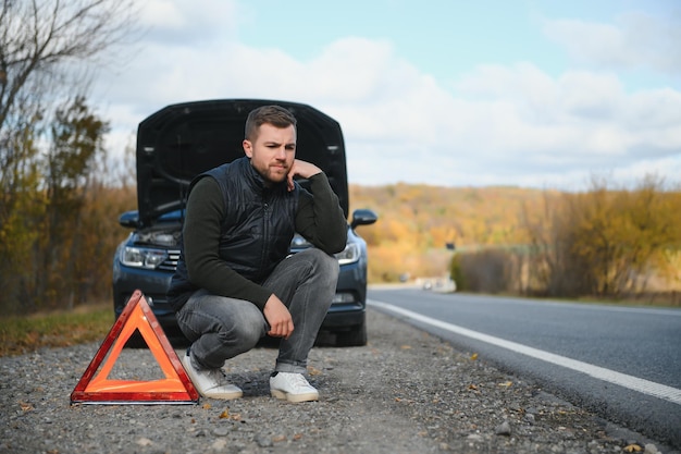 Foto un hombre siente estrés porque su auto está averiado