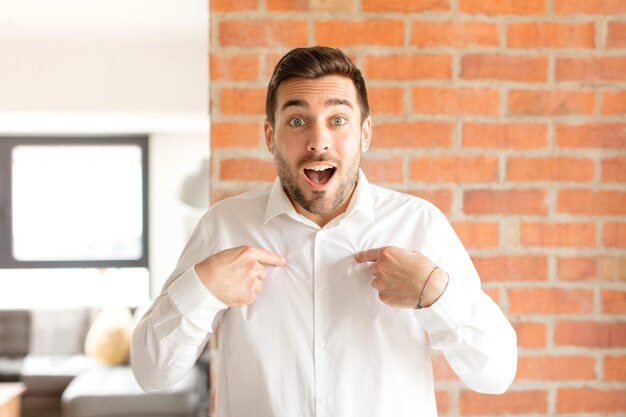 El hombre se siente feliz, sorprendido y orgulloso, apuntando a sí mismo con una mirada emocionada y asombrada