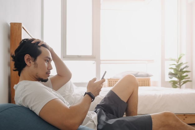 El hombre se siente relajado y usando el teléfono inteligente en su apartamento