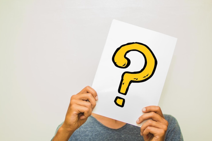 Foto hombre con un signo de pregunta en el papel contra un fondo gris