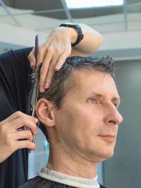 Hombre en silla de peluquero cortando su cabello