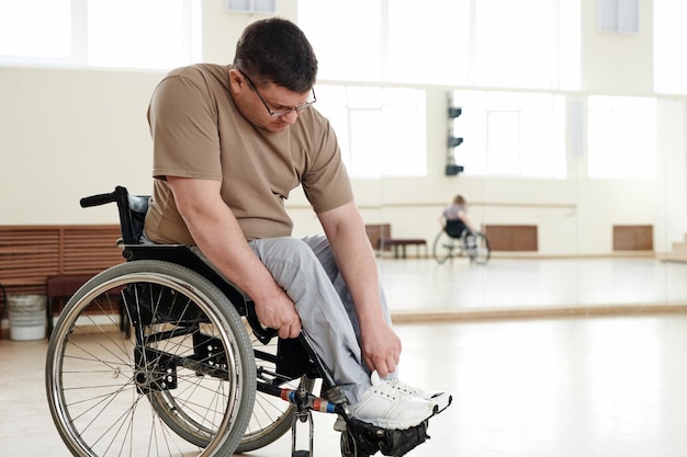 Hombre en silla de ruedas arreglando su pierna