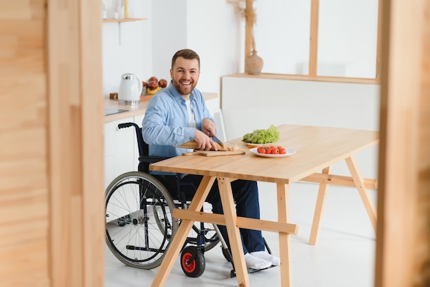 Hombre en silla de ruedas corta verduras en la cocina