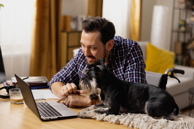 Un hombre en silla de ruedas se sienta en su escritorio y navega por sitios web dedicados a camas para perros.