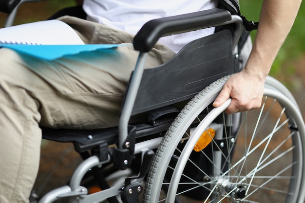 Hombre en silla de ruedas sostiene la rueda con la mano
