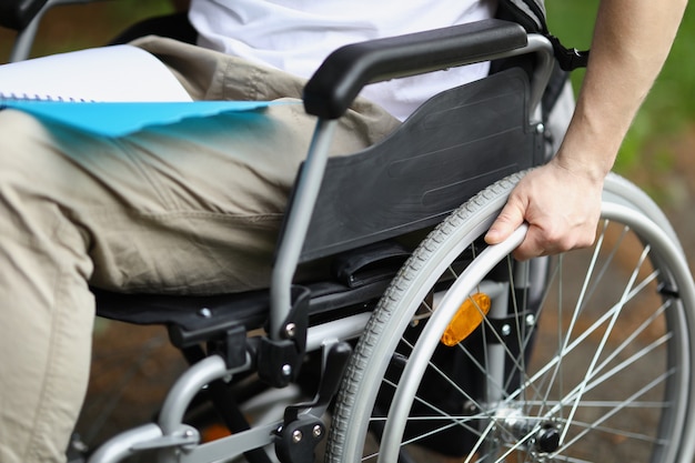 Foto hombre en silla de ruedas tiene rueda con la mano