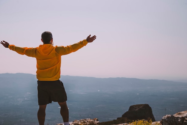 Hombre silueta levantando las manos en la montaña por la mañana con luz vintage