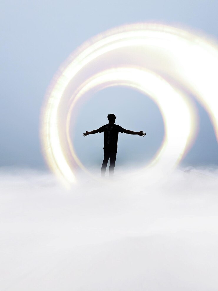 Foto hombre silueta con luz de pie en el cielo nublado