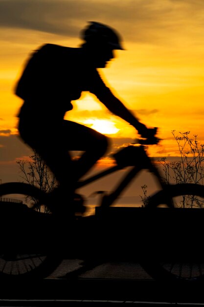 Hombre silueta montando en bicicleta contra el cielo durante la puesta de sol