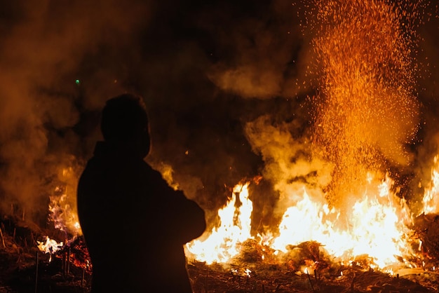 Hombre de silueta parado frente al fuego