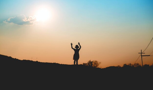 Foto hombre silueta de pie en el campo contra el cielo durante la puesta de sol