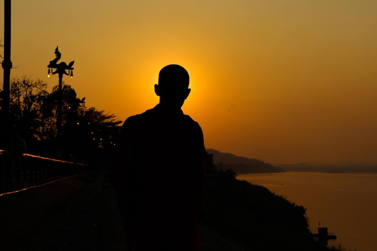 Foto hombre silueta de pie contra el cielo naranja durante la puesta de sol