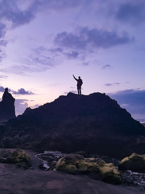 Foto hombre silueta de pie en la montaña contra el cielo durante la puesta de sol