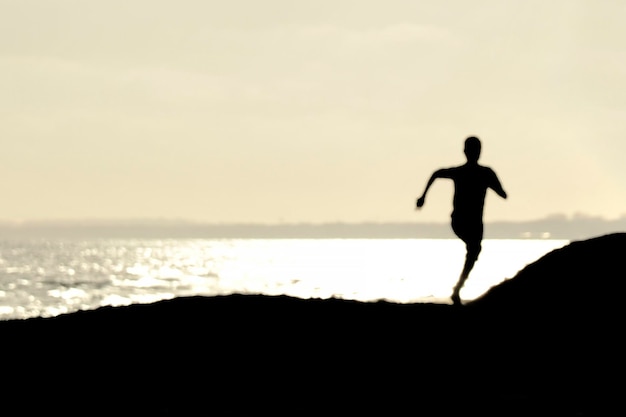 Hombre silueta de pie en la playa contra el cielo durante la puesta de sol