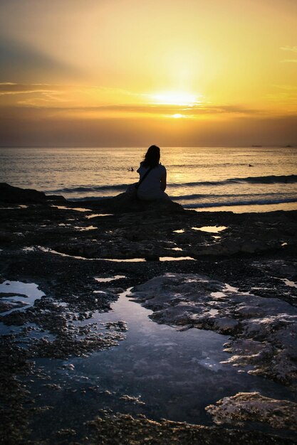 Hombre silueta en la playa contra el cielo durante la puesta de sol