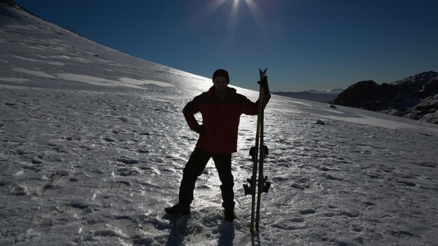 Hombre silueta con tabla de esquí de pie sobre la nieve