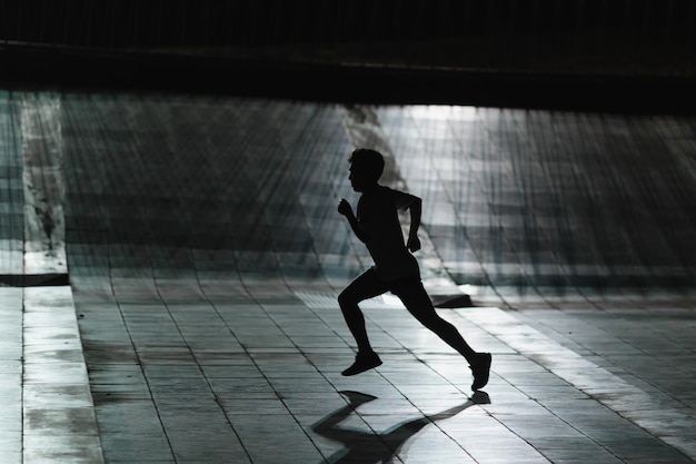 El hombre de silueta de toda la longitud corriendo en el túnel