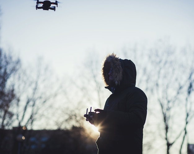 Hombre silueta usa drones al aire libre con puesta de sol