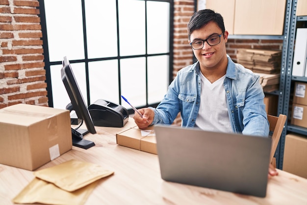 Hombre con síndrome de Down trabajador de negocios de comercio electrónico escribiendo en un paquete en la oficina