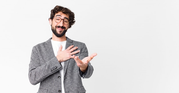 hombre sintiéndose feliz y enamorado, sonriendo con una mano al lado del corazón y la otra estirada al frente