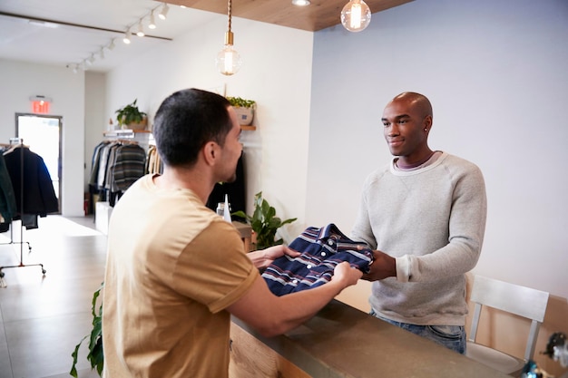 Hombre sirviendo al cliente en el mostrador de una tienda de ropa