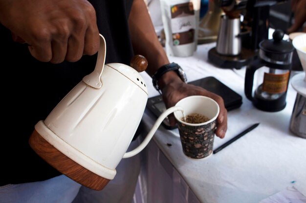 Un hombre sirviendo café en una taza